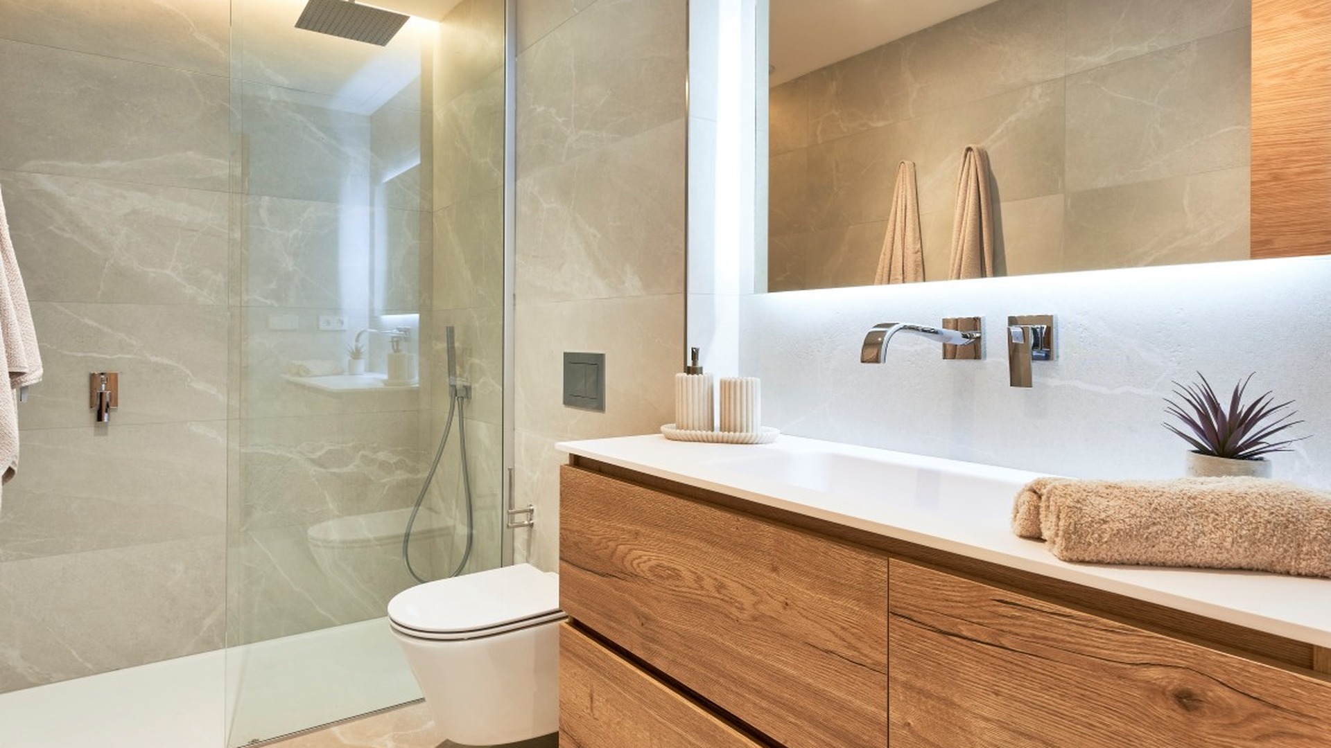 Łazienka w inwestycji ES Voltor, Esporles: prysznic walk‑in, wisząca toaleta, drewniana szafka i podświetlane lustro.