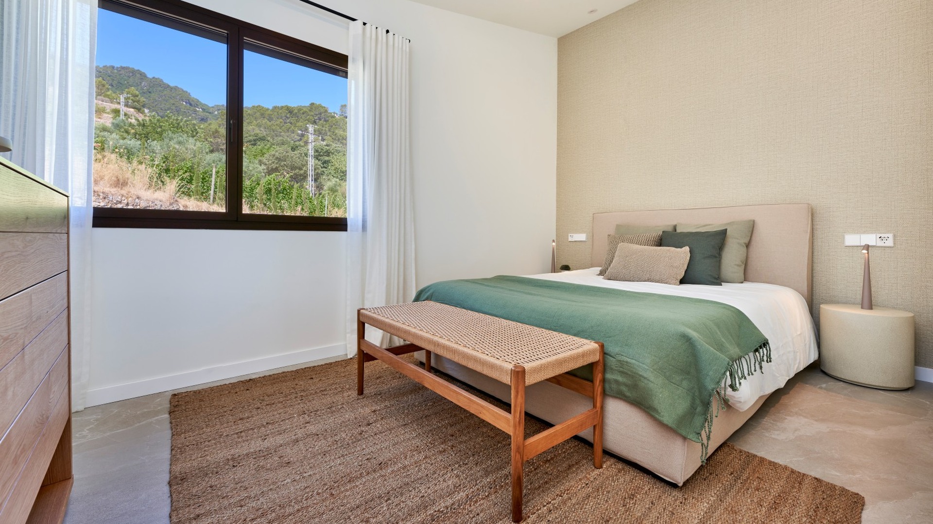 Sypialnia w ES Voltor z szerokim oknem, łóżkiem małżeńskim i plecioną ławką u wezgłowia.