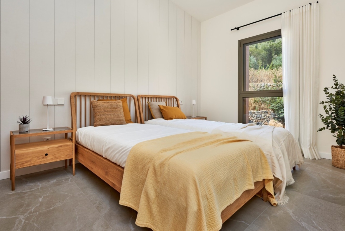 Pokój gościnny z dwoma łóżkami, drewnianymi meblami i oknem – inwestycja ES Voltor w Esporles.