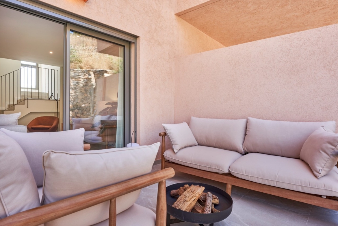 Zbliżenie na patio z sofami ogrodowymi i kominkiem ogrodowym – inwestycja ES Voltor, Esporles.