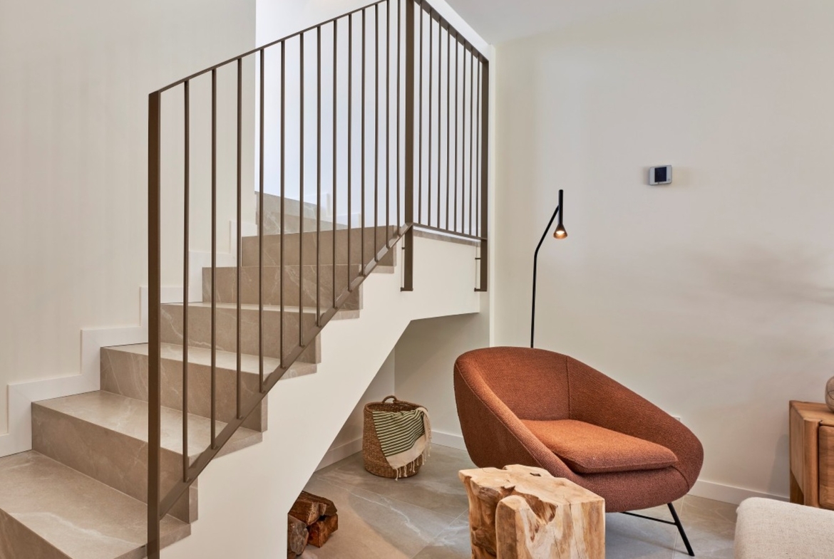 Salon z wygodnym fotelem i schodami wykończonymi kamieniem w inwestycji ES Voltor, Esporles.