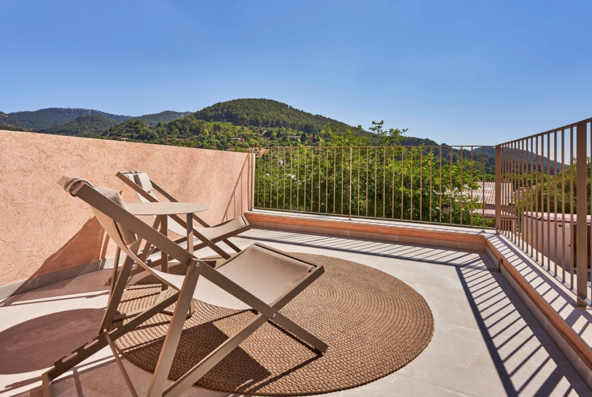 Taras z dwoma leżakami i stolikiem, widok na zielone wzgórza Serra de Tramuntana – ES Voltor, Esporles.