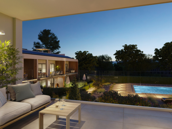 Zadaszony balkon z sofą i widokiem na podświetlony basen nocą.