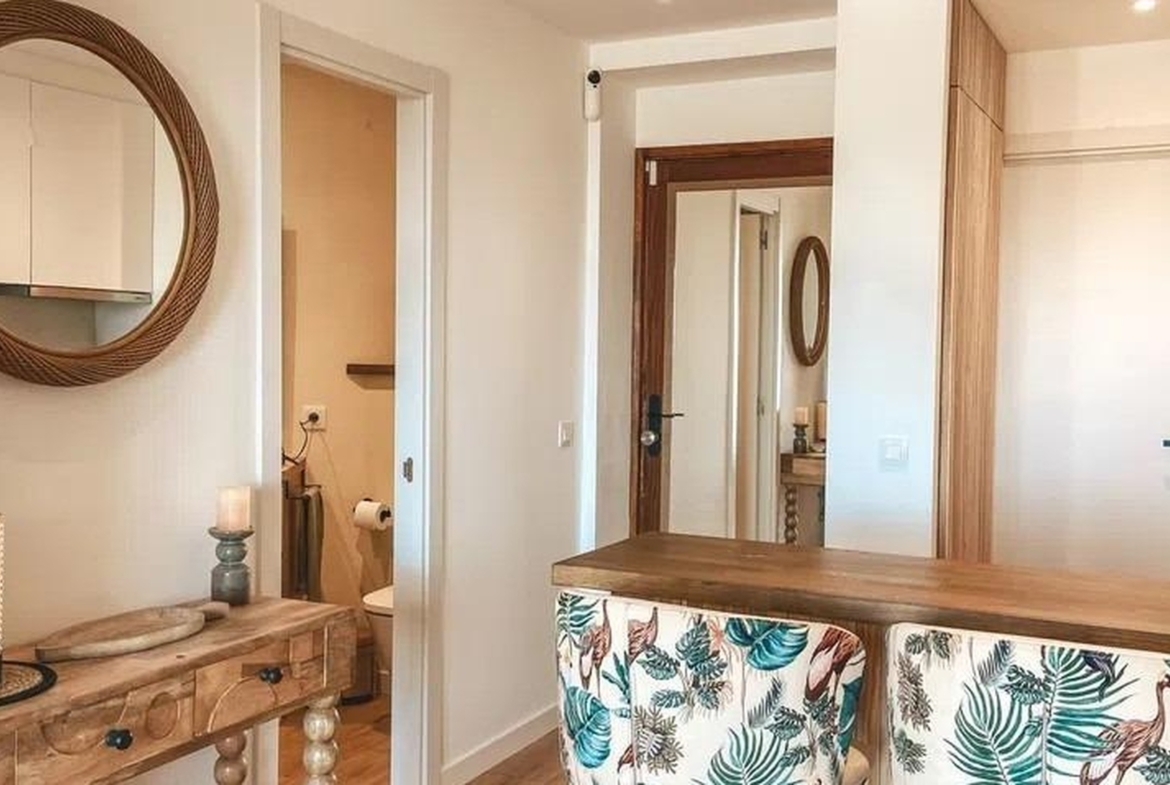 Widok na korytarz i wyspę barową z tapicerowanymi hokerami w apartamencie w Sant Agustí.