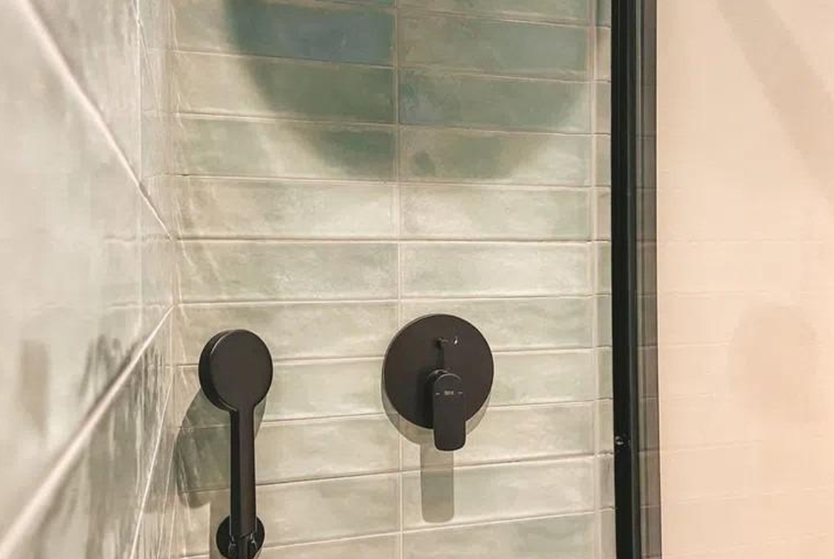Strefa prysznica z zielonymi płytkami i czarną armaturą – apartament w Sant Agustí, Palma.